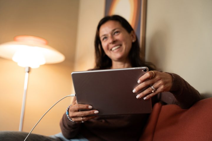 Kvinde sidder i sin sofa og overvejer at vælge en afbetalingsløsning til sit nye hjemmebatteri fra Andel Energi